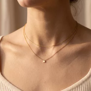 Céleste Layered Necklace worn at the neck: two fine gold chains, the lower one with a tiny star charm