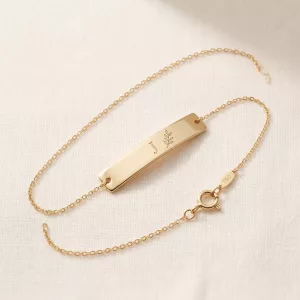 Gold bar bracelet engraved with an initial and a leaf sprig
