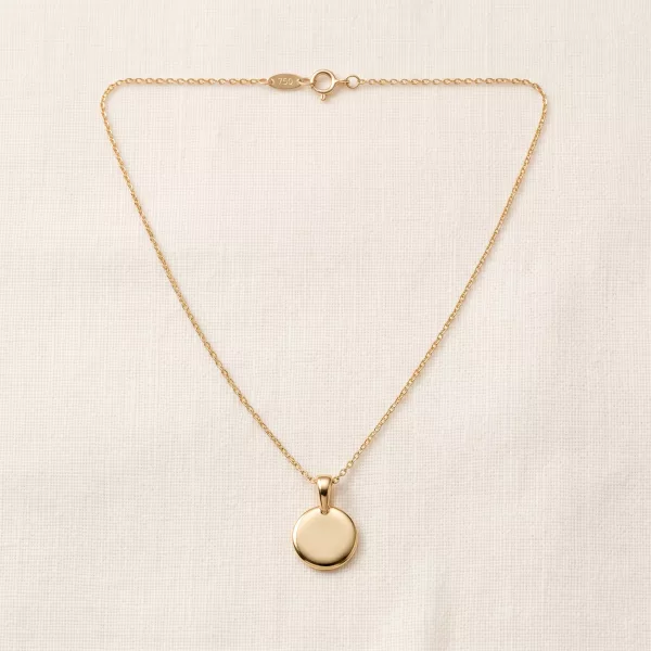 Soleil Medallion Necklace laid flat on linen: polished gold disc on a fine cable chain