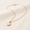 Soleil Medallion Necklace at a three-quarter angle, the polished disc resting on linen