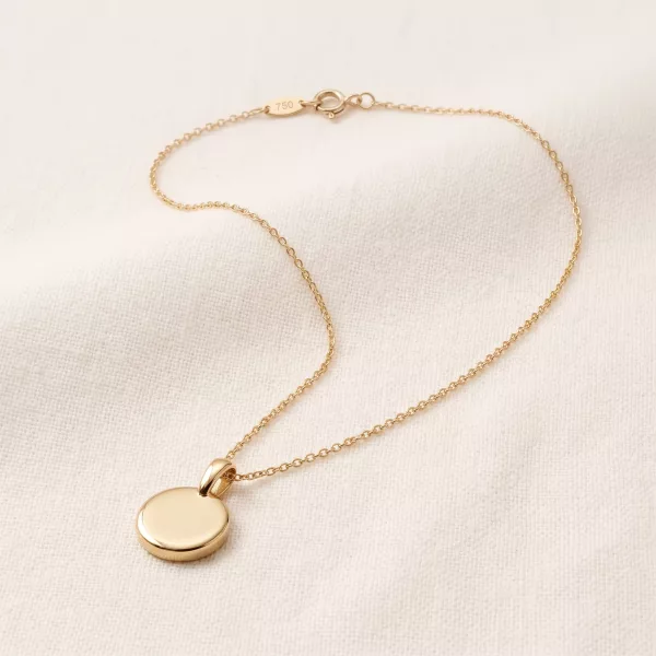 Soleil Medallion Necklace at a three-quarter angle, the polished disc resting on linen