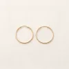 Pair of fine gold hoop earrings on linen