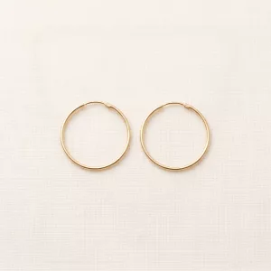 Pair of fine gold hoop earrings on linen