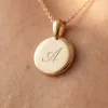 Close-up of the polished gold disc engraved with a script initial A