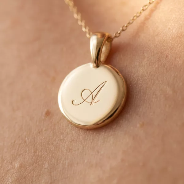 Close-up of the polished gold disc engraved with a script initial A